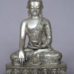 Seated silver-tone Buddha statue with intricate engraved detailing.