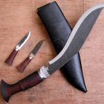 Traditional Nepali khukuri with wooden handles and black sheath, shown with smaller knives.